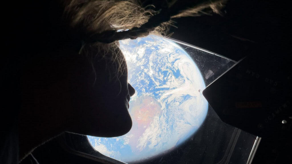 Astronauta Christina Koch na janela da Orion olhando para a Terra durante a Artemis 2