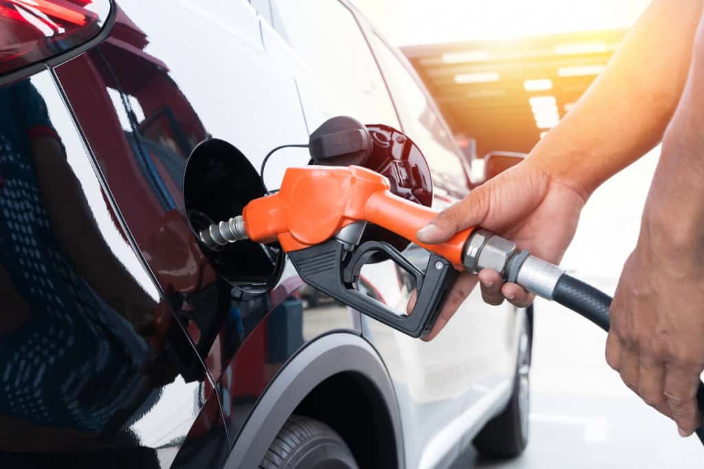 Pessoa abastece carro em posto de combustível com bomba de gasolina