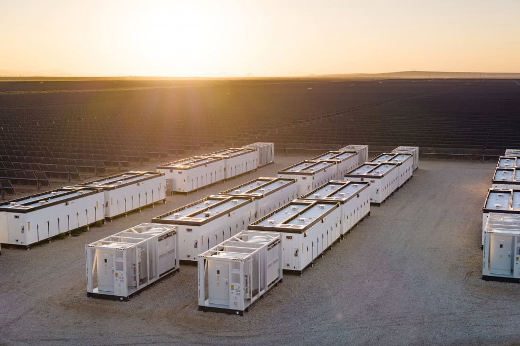 Sistema de armazenamento de energia em baterias instalado ao lado de um parque solar, tecnologia que permite armazenar eletricidade para uso quando a geração das fontes renováveis diminui.