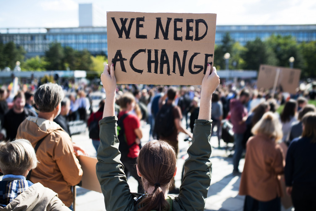 mulher segurando um cartaz pedindo mudanças em manifestação