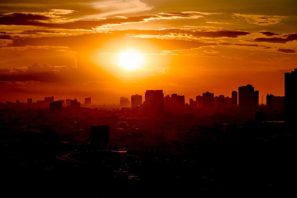 Sol forte no horizonte com a cidade abaixo, na sombra