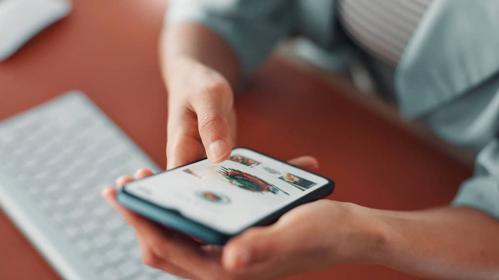Pessoa segura um smartphone com um aplicativo de pedidos de comida aberto na tela.